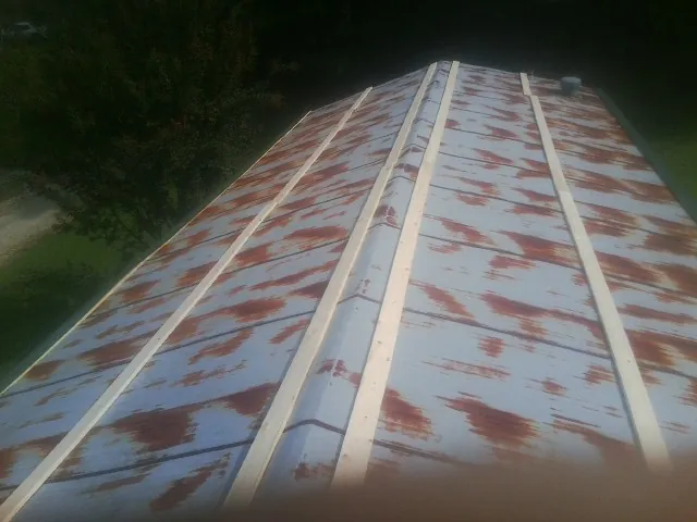 Rusted metal roof panels with new wood purlins before replacement — Storm Damage Roof Repair in Encampment by Roofing Brothers