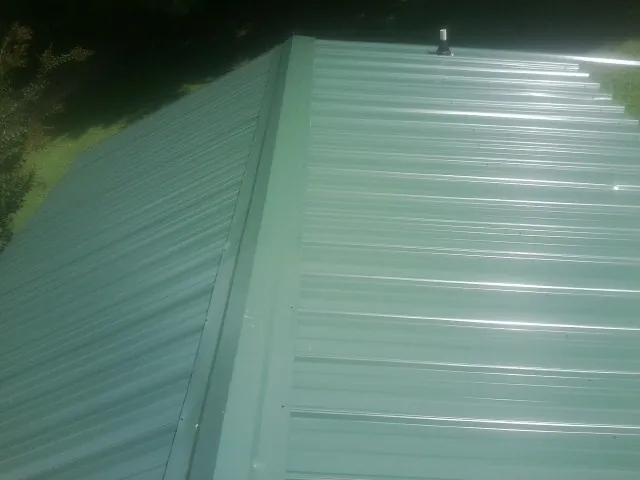 New green metal panels meeting at the ridge of a roof — Flat Roof Repair work by our crew in Encampment