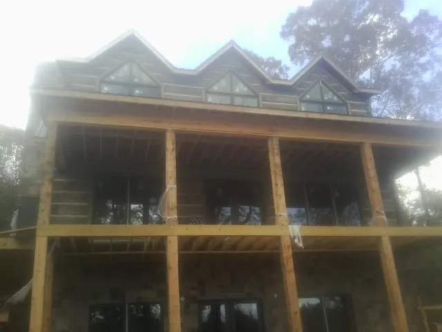 Dormers and porch framing on a large log home under construction — Roof Coating work by our crew in Encampment