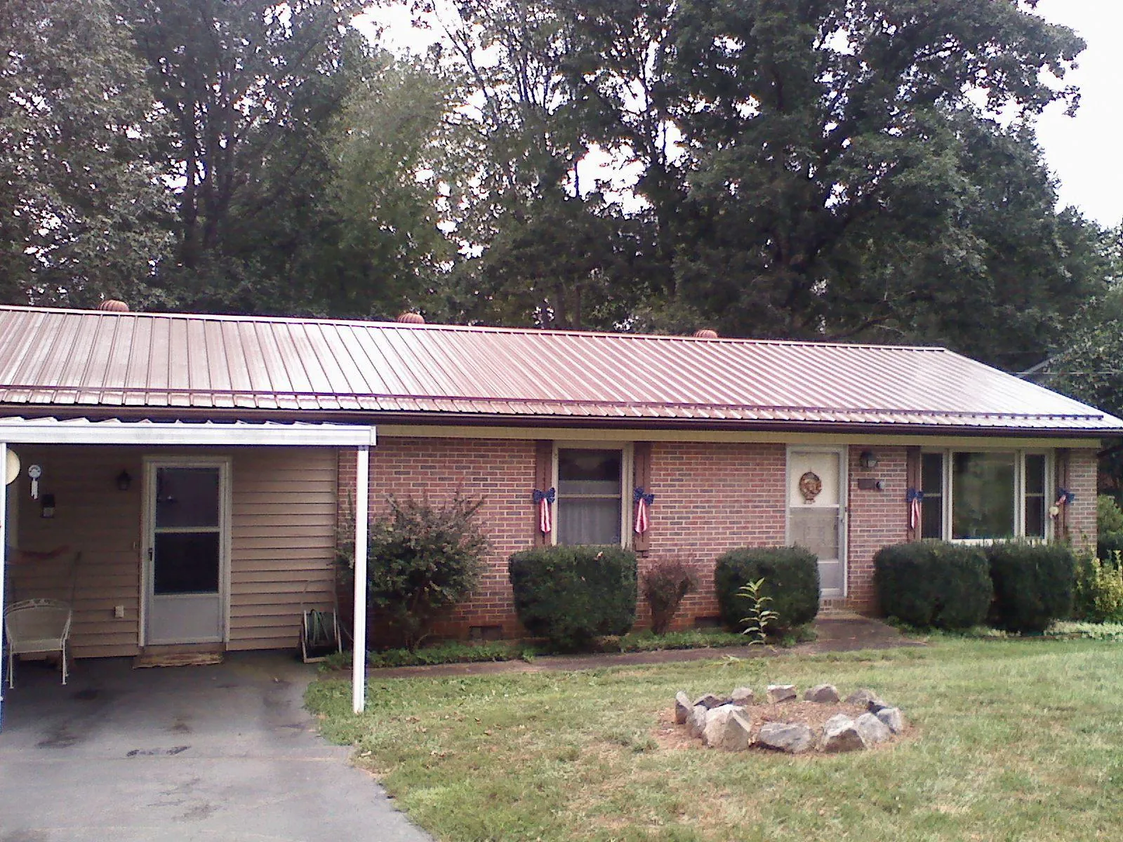 Bronze metal roof and carport on a brick ranch home — Roof Repair work by our crew in Encampment