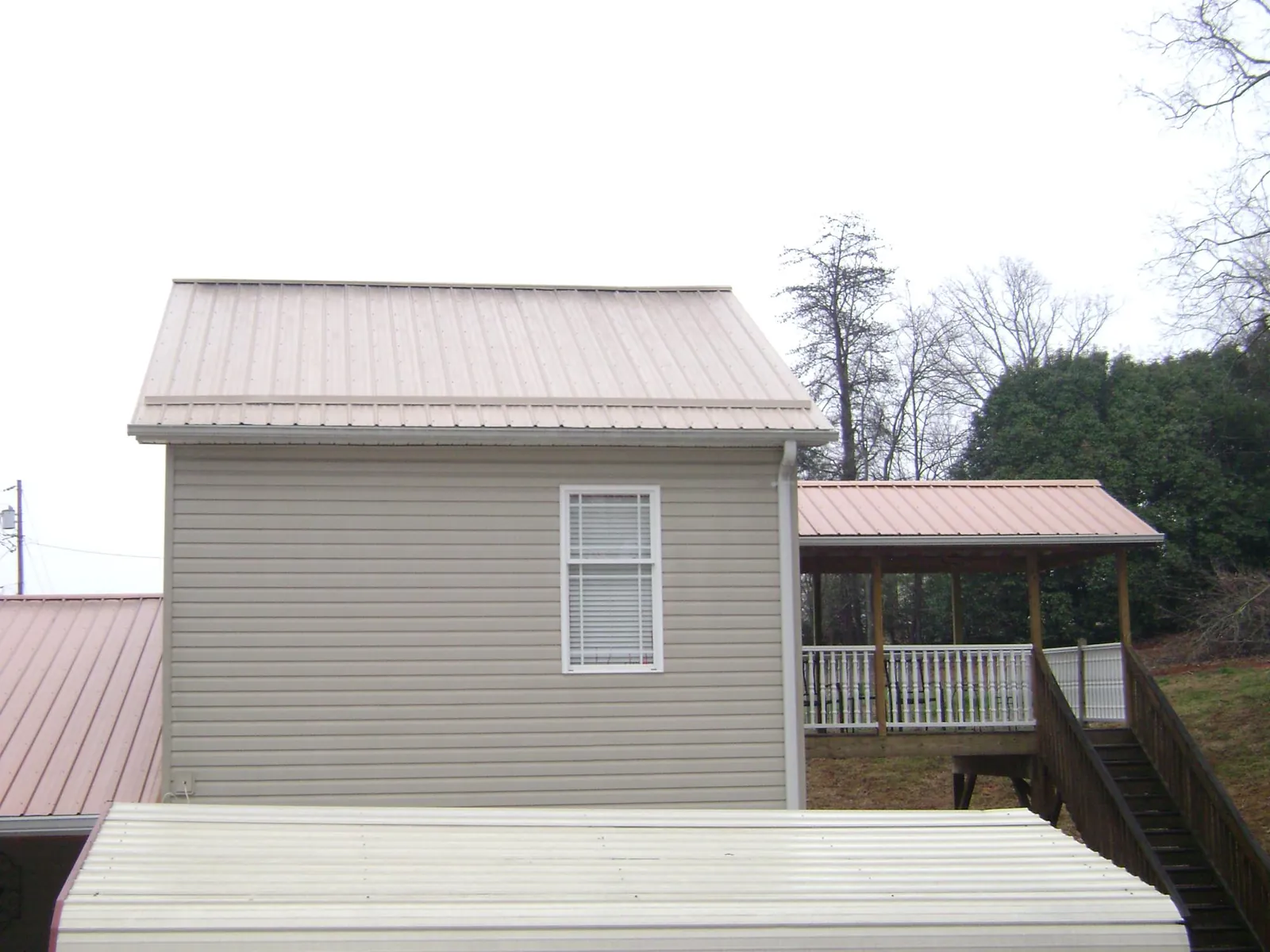 Tan metal roofs on a two story addition and attached porch, from a Roof Replacement job in Encampment