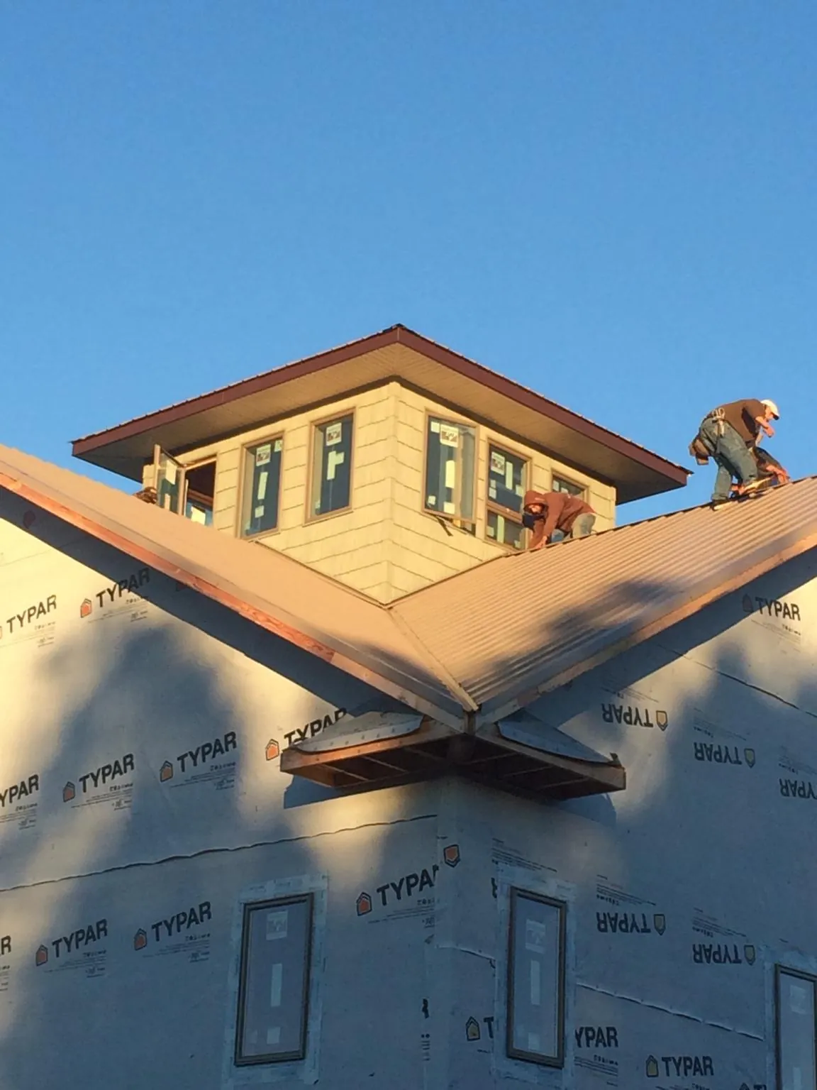 Roofers working around a rooftop cupola on a new metal roof at sunset — Roof Waterproofing in Encampment by Roofing Brothers